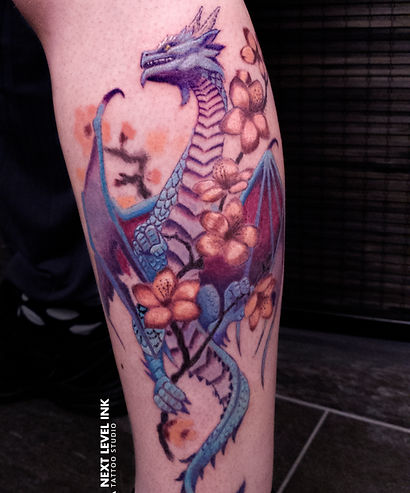 Blauwe en paarse draak met oranje bloemen op onderbeen.