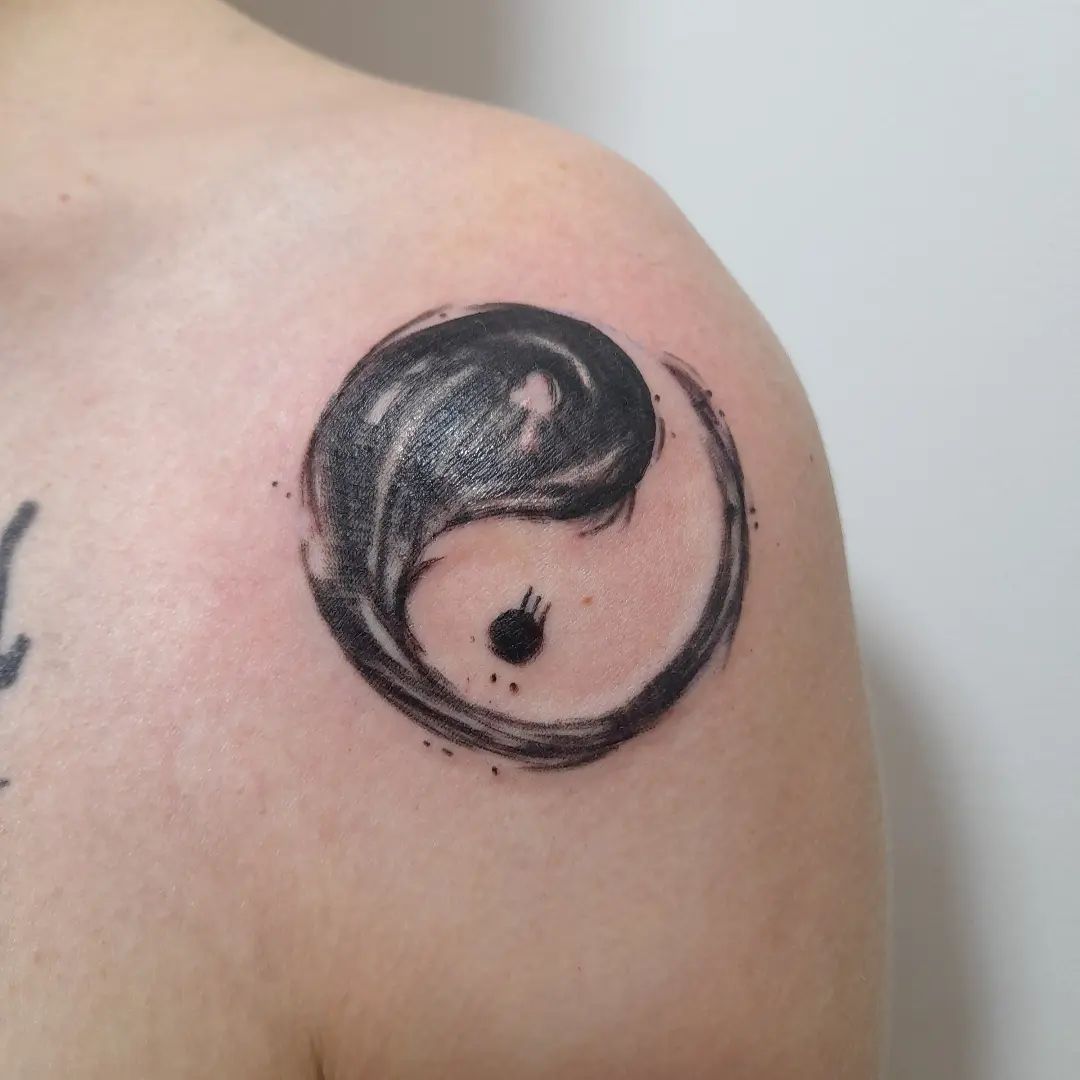 Yin Yang tattoo in penseelstreek stijl op de schouder.