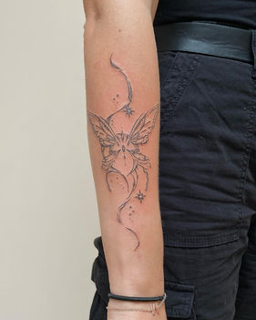 Fineline vlinder met sierlijke lijnen en sterretjes op de onderarm.