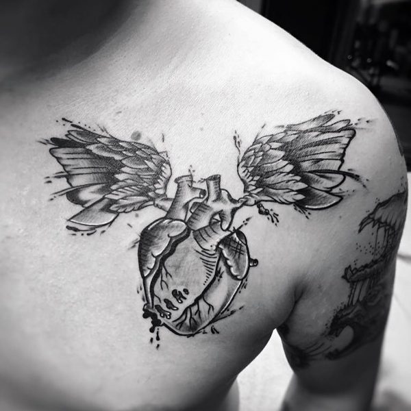 Zwart-wit tattoo van een anatomisch hart met vleugels op de borst.