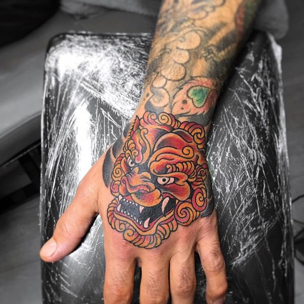 Kleurrijke Japanse Foo Dog tattoo op de hand.