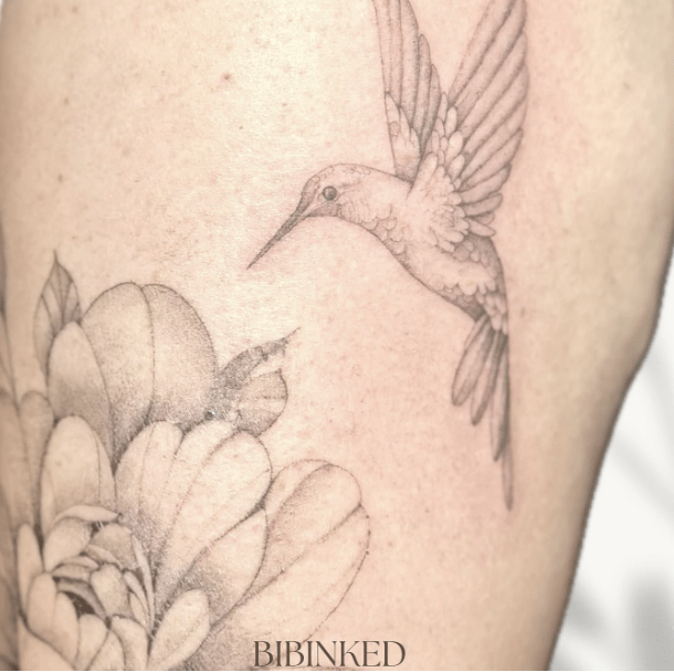 Fineline tattoo van een kolibrie en een bloem.