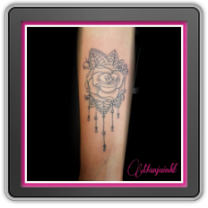 Fineline roos met mandala bladeren en hangende parels op onderarm.