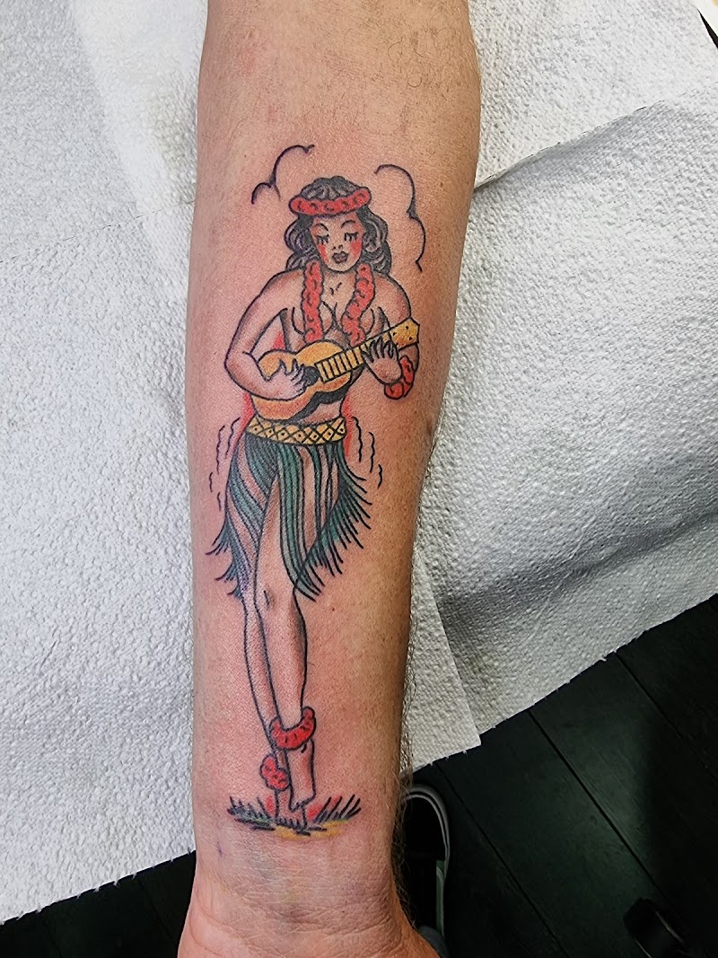 Traditional tattoo van een hula meisje met ukelele op de onderarm.