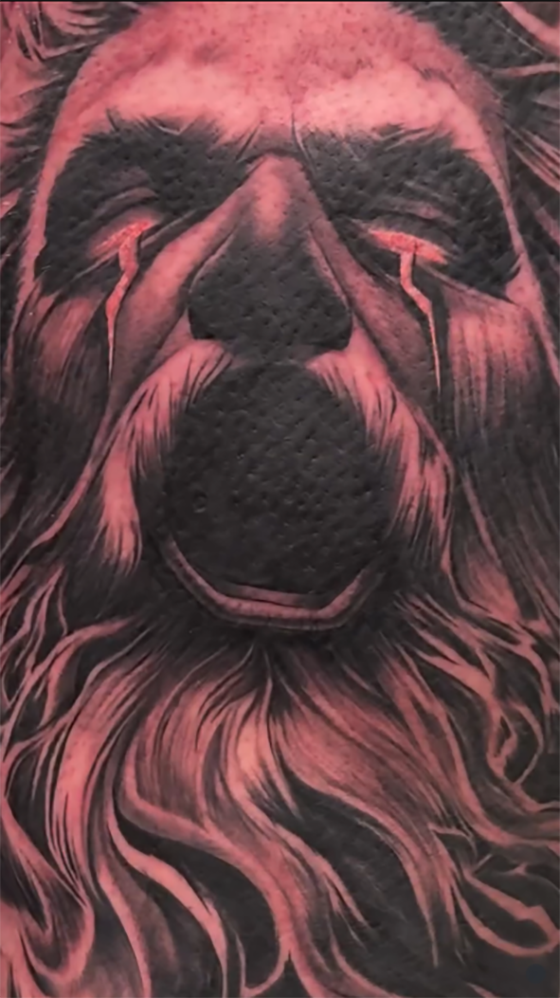 Duistere Zeus tattoo met rode gloeiende ogen en baard.