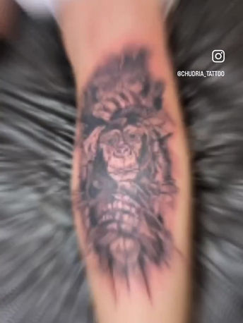 Zwart-wit tattoo van een aap met een kroon op het onderbeen.