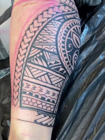 Grote Polynesische tribal tattoo op onderbeen, deels ingekleurd.