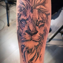 Sketch-style leeuwenkop tattoo op de onderarm.