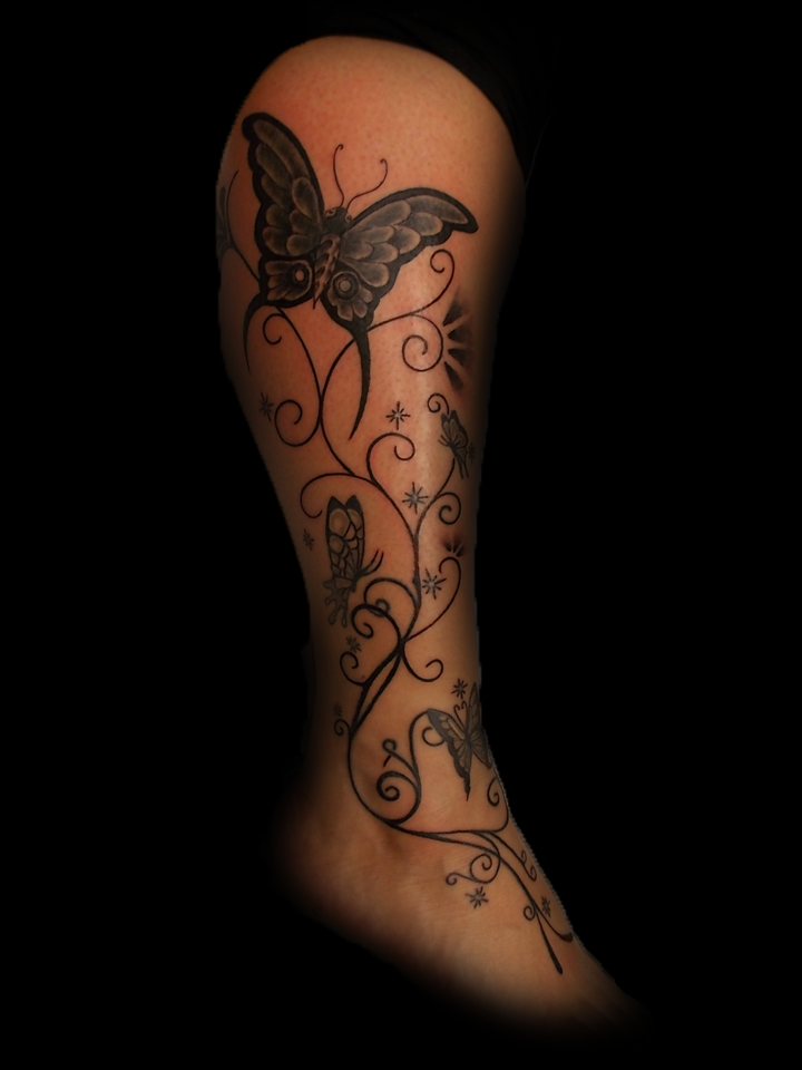 Zwart-wit vlinders en sierlijke ranken op onderbeen en voet.