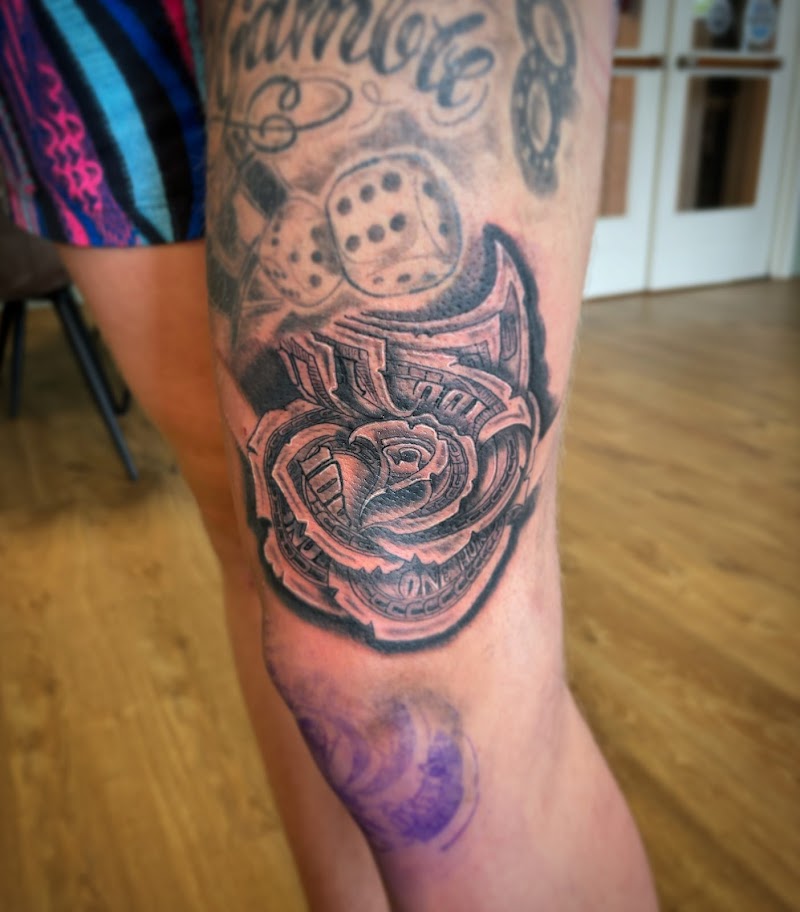 Zwart-wit tattoo van een roos gevouwen uit dollarbiljetten op het bovenbeen.