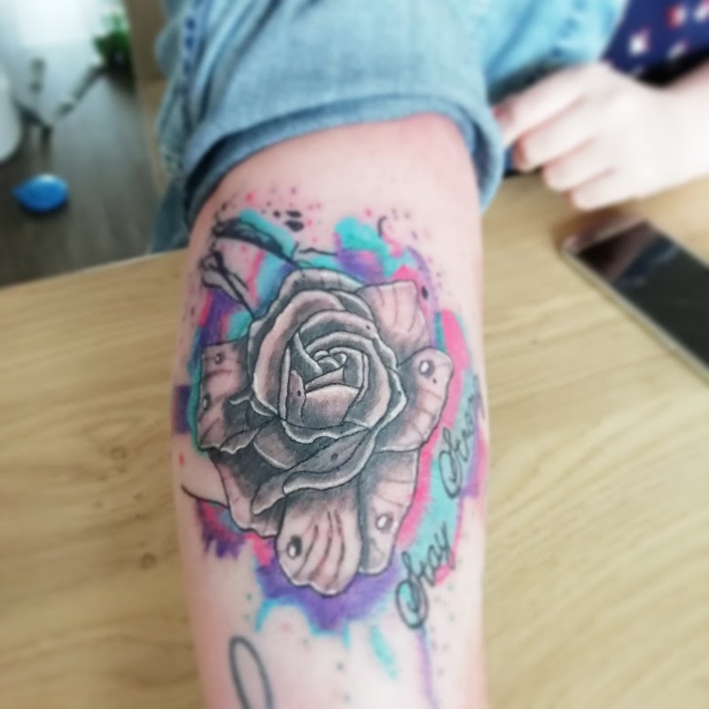 Watercolor roos tattoo met tekst 'Stay Strong' op onderarm.