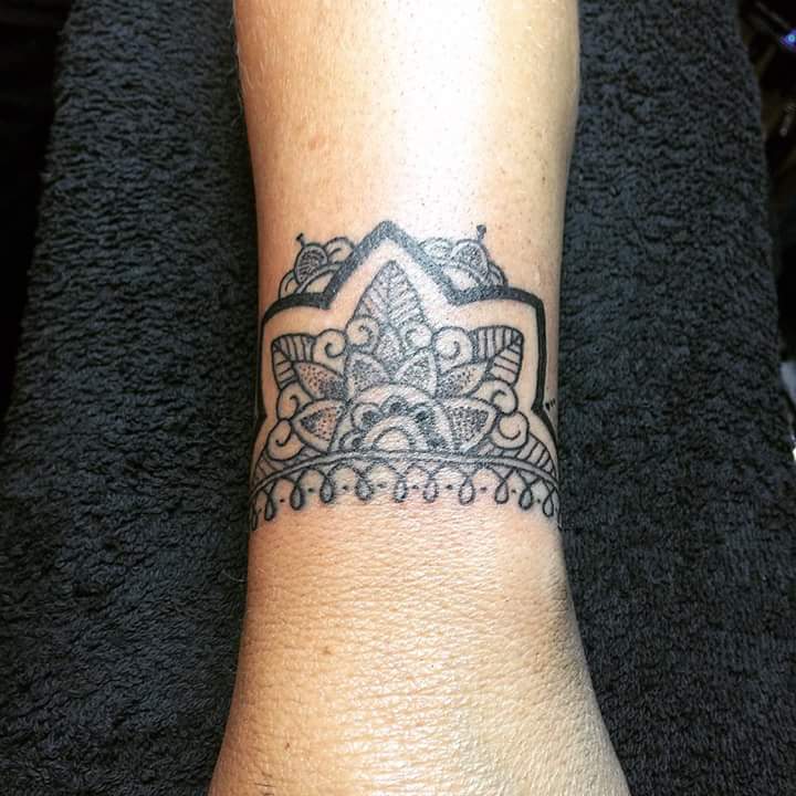 Zwart-wit mandala polsband tattoo met dotwork en sierlijke lijnen.