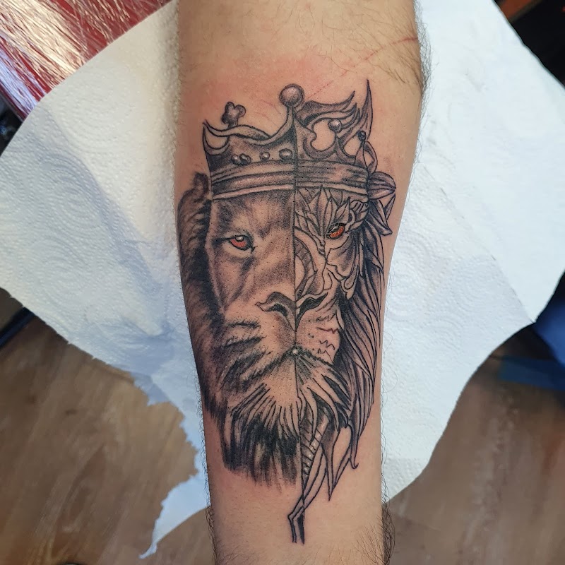 Halve leeuw, halve draak met kroon en rode ogen op onderarm.