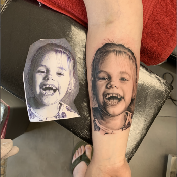 Realistisch portret van een lachend kind op de onderarm.