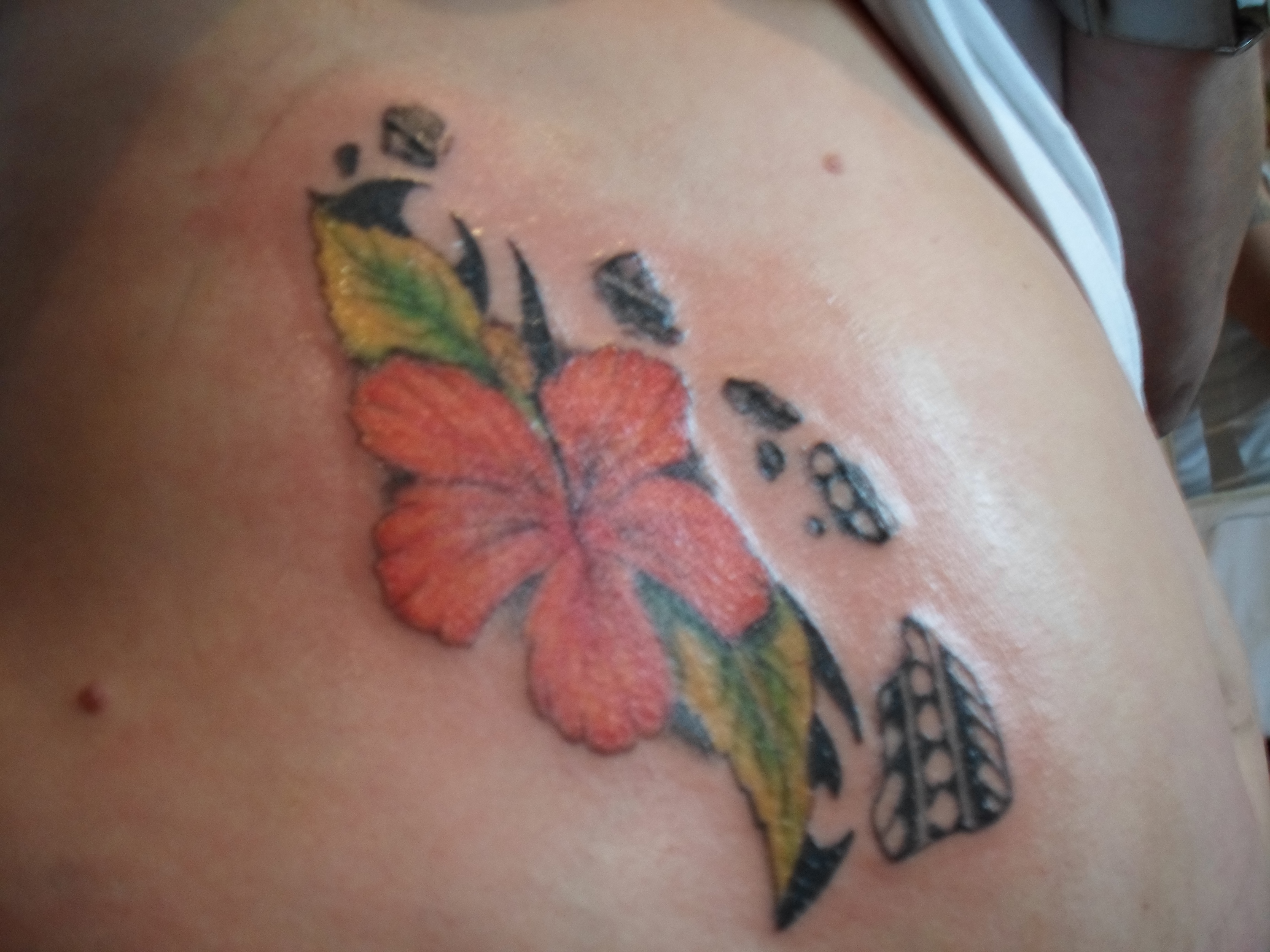 Rode hibiscus bloem met groene bladeren en zwarte tribal patronen.