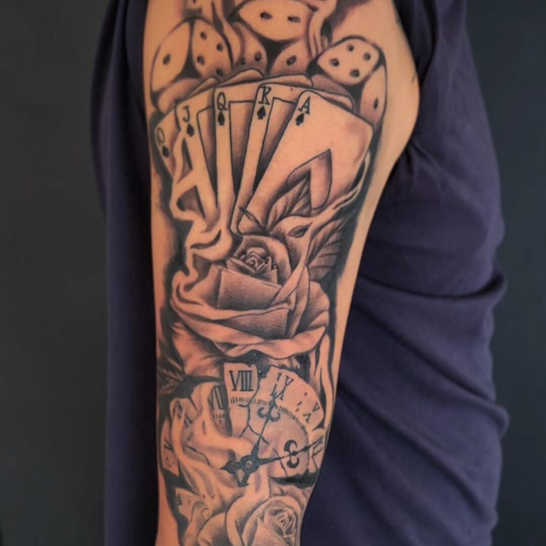 Zwart-wit half-sleeve met kaarten, dobbelstenen, roos en klok.