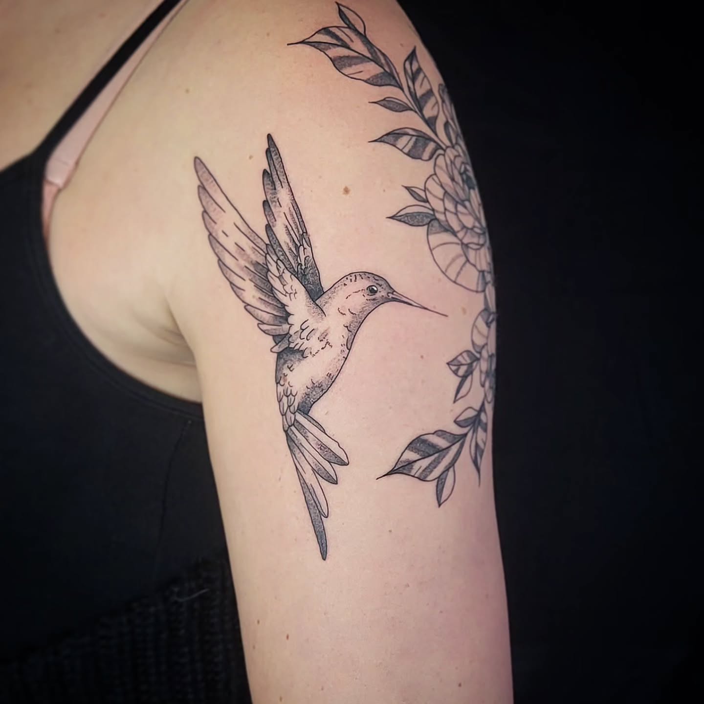 Blackwork kolibrie en bloemen op bovenarm.