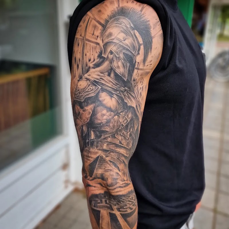 Gedetailleerde zwart-wit tattoo van een Spartaanse krijger op de bovenarm.