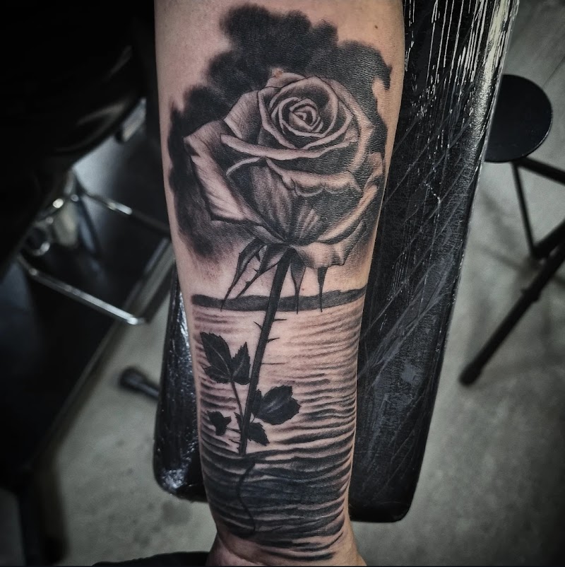 Realistische roos in water op onderarm, zwart-wit.