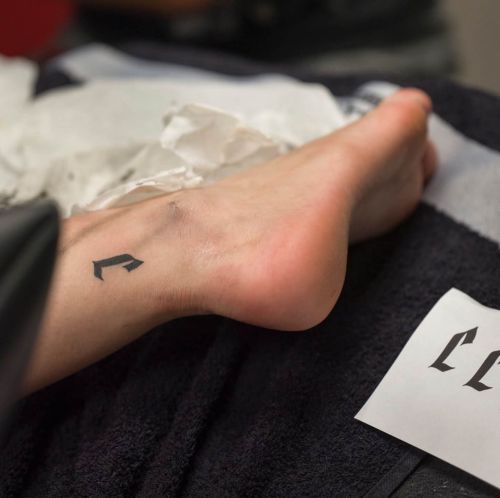 Kleine gotische letter 'C' tattoo op de enkel.