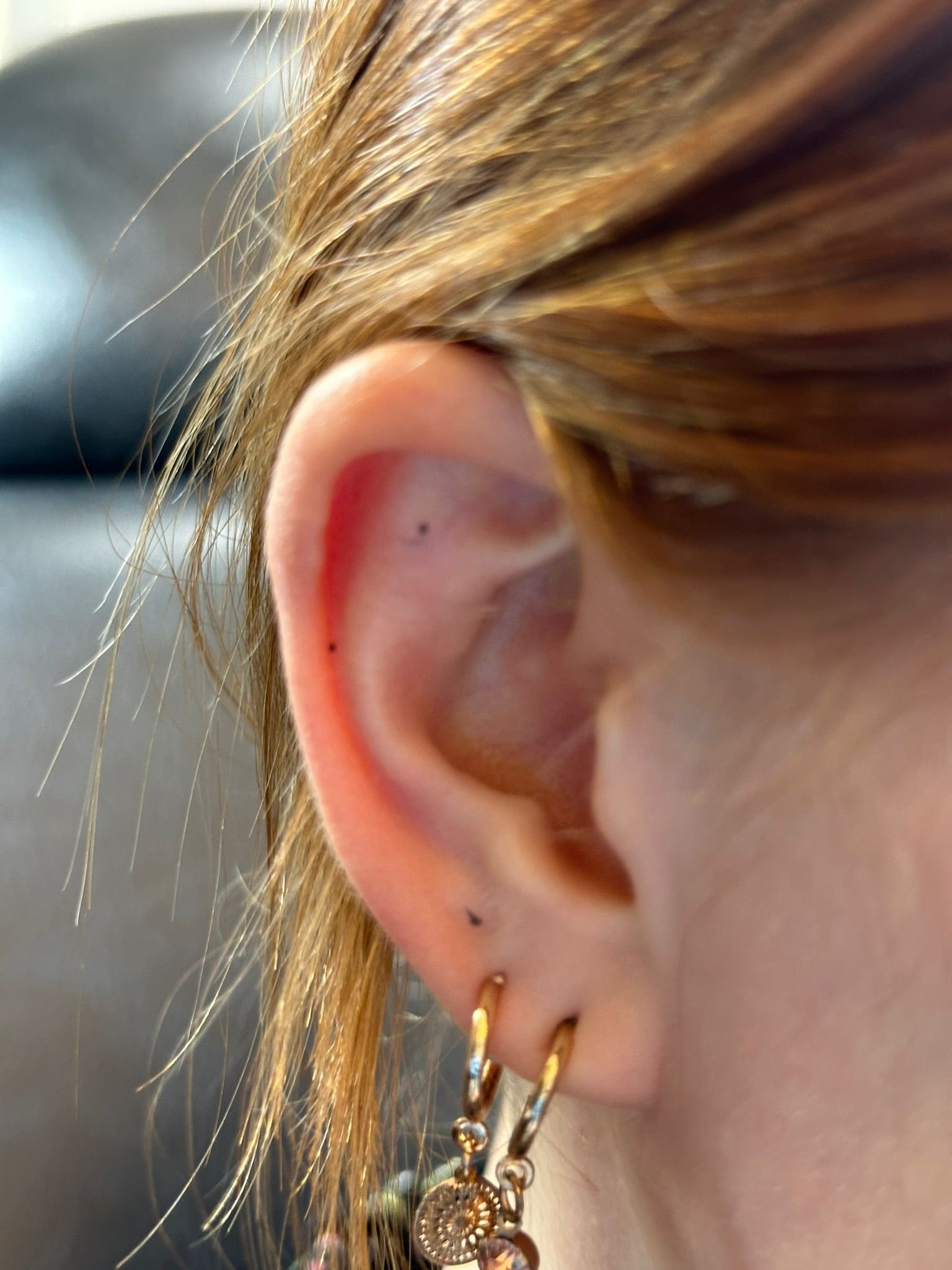 Minimalistische drie stippen tattoo op het oor.