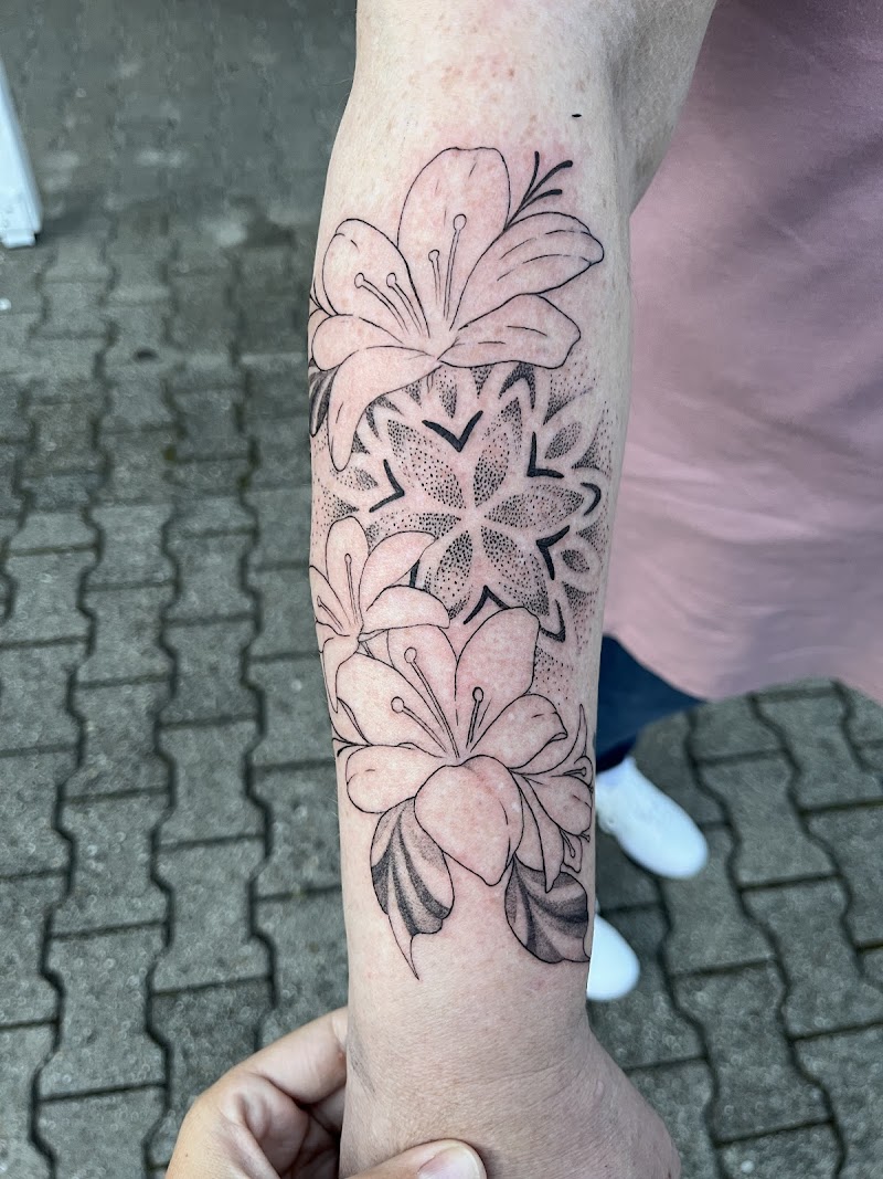Fineline bloemen en dotwork mandala op onderarm.