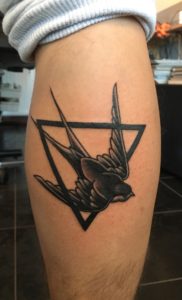 Zwart-witte zwaluw in een driehoek op het onderbeen.