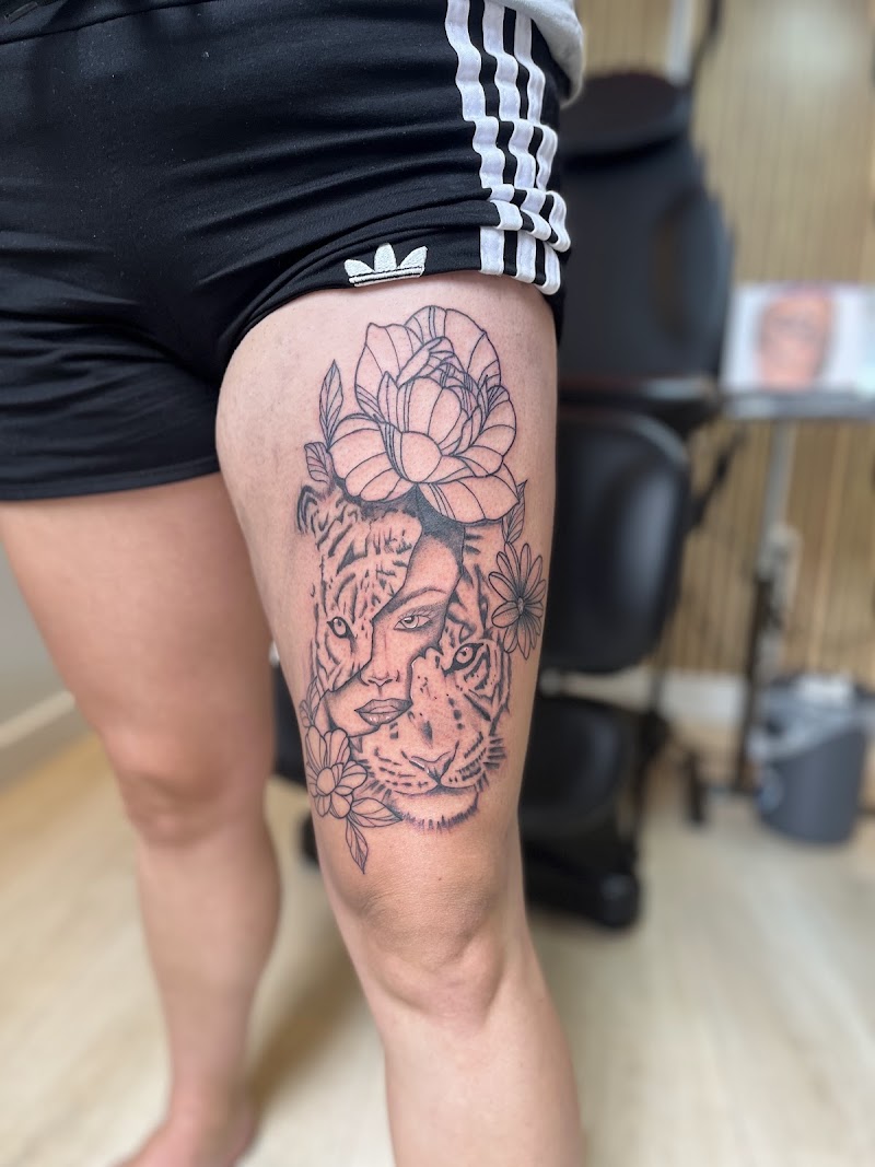 Tijger en vrouwengezicht morph met bloemen op bovenbeen.