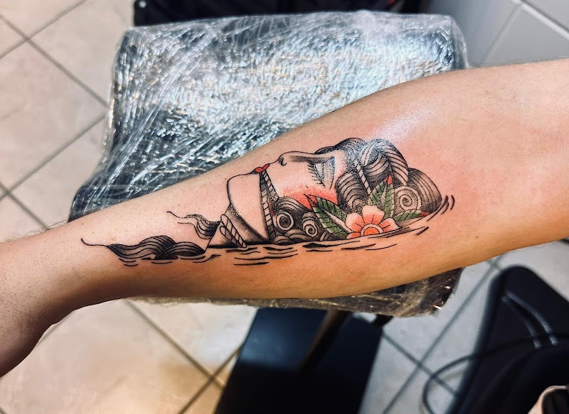 Traditional tattoo van een vrouwenhoofd in water met een bloem.