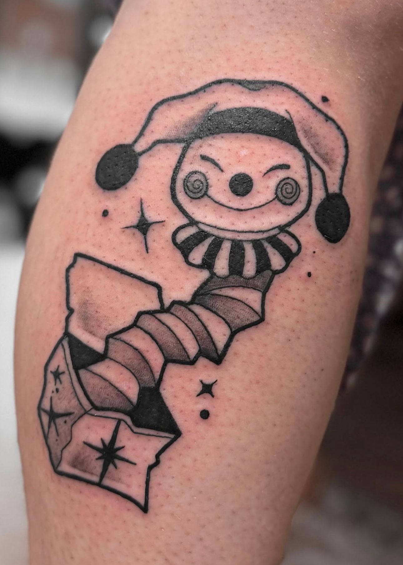 Zwart-wit jack-in-the-box clown tattoo op onderbeen