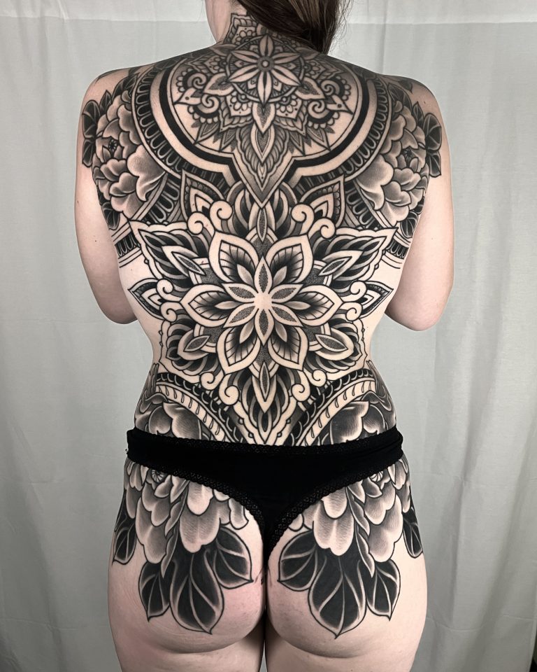 Grote zwart-wit mandala en bloemen backpiece tattoo.