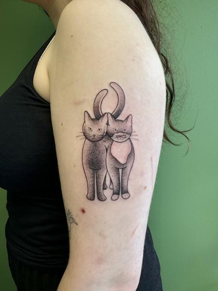 Twee grijze katten in dotwork stijl, één met een roze doekje, op de bovenarm.