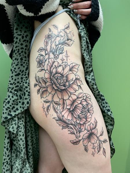 Grote bloemen tattoo op de heup in blackwork stijl.