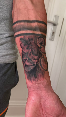 Realistische leeuwenkop met zwarte banden op onderarm.