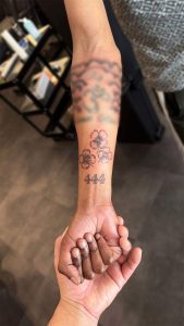 Drie bloemen en het getal 444 op de onderarm.