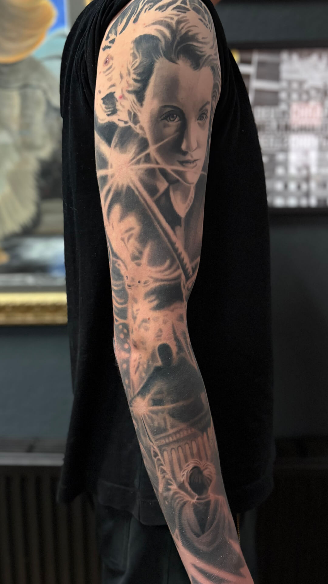 Realistische sleeve tattoo met portret en architectuur op arm.