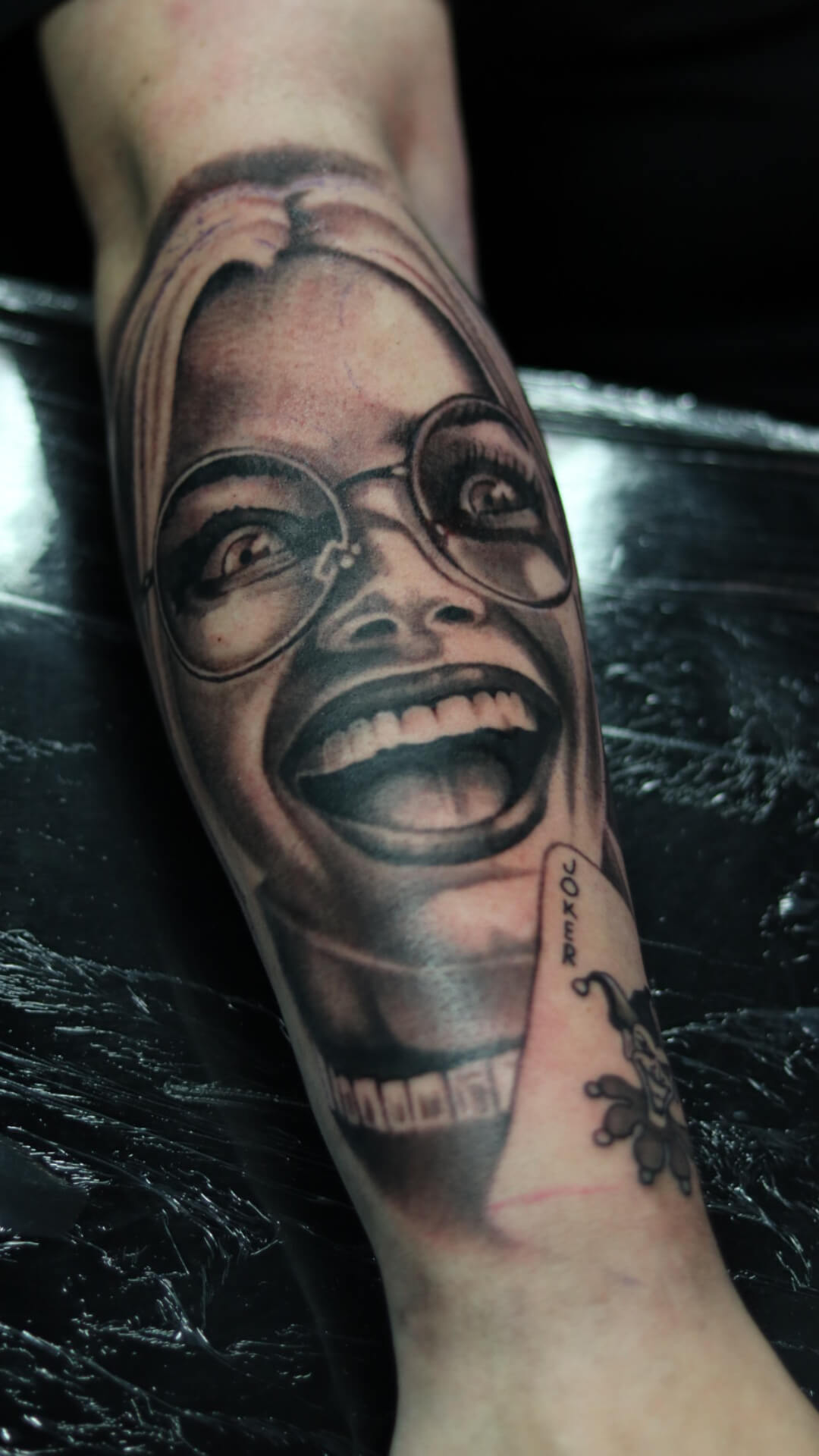 Realistisch portret van lachende vrouw met bril en een Joker kaart.