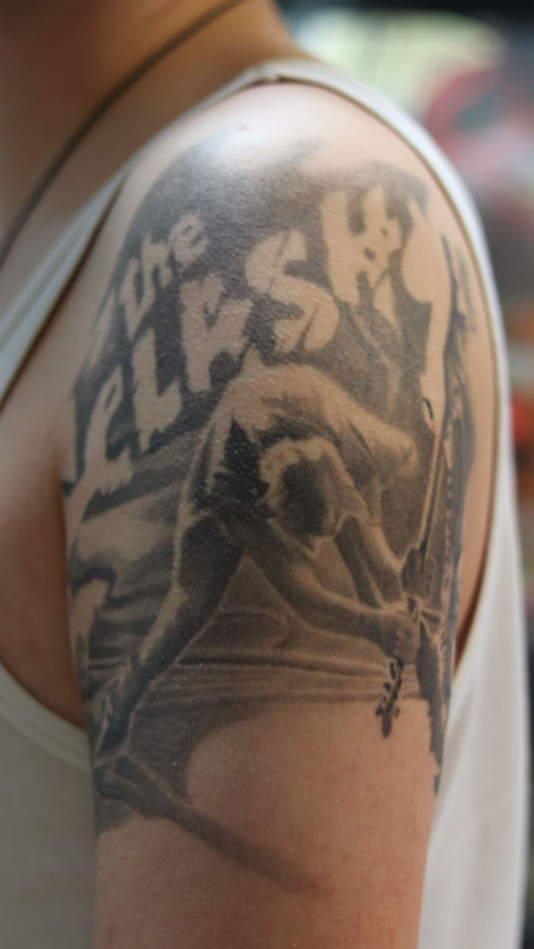 Zwart-wit tattoo van The Clash 'London Calling' album cover op bovenarm.