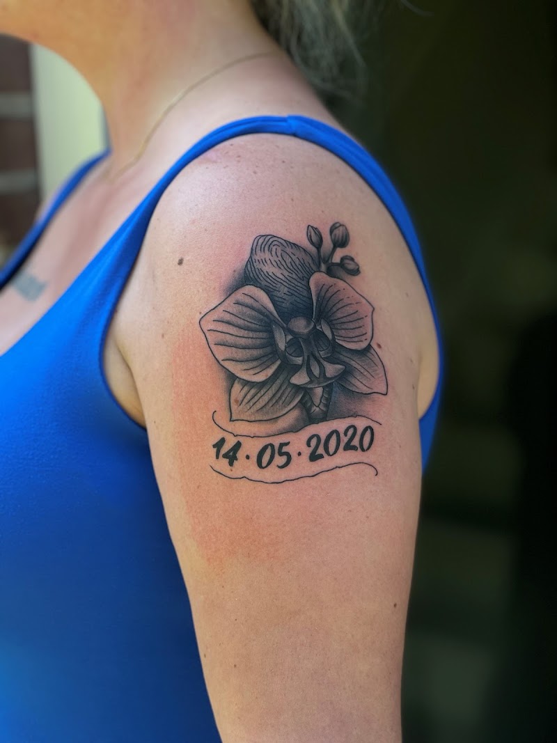 Blackwork orchidee met datum 14.05.2020 op bovenarm.