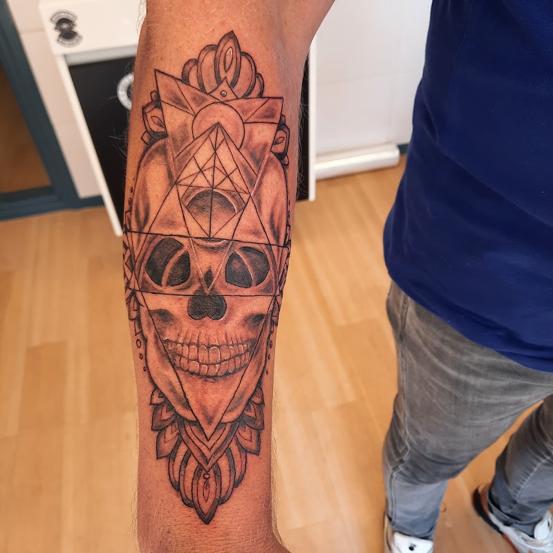 Zwart-wit schedel met geometrische vormen en mandala op onderarm.