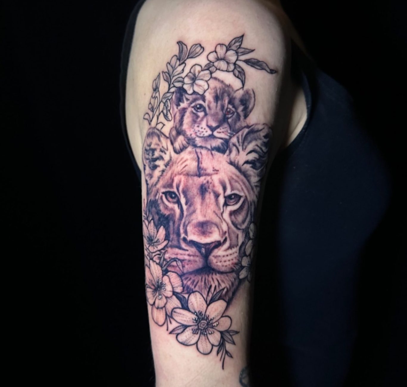 Realistische leeuwin met welp en bloemen op bovenarm.