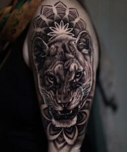 Realistische leeuwin met mandala op bovenarm.