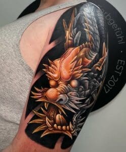 Grote, gedetailleerde draak tattoo in kleur op de bovenarm.
