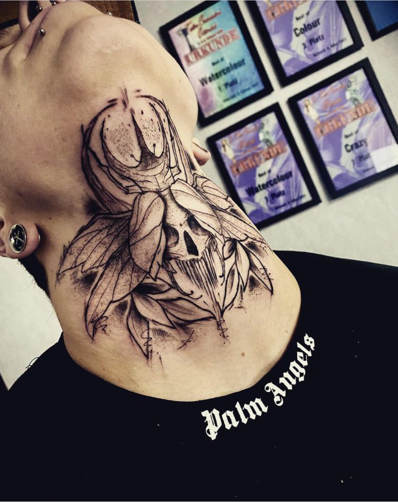 Grote nek tattoo van een kever met een doodskop op het lijf en bladeren.