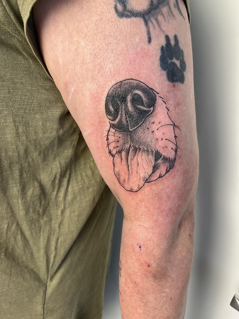 Realistische hondenneus en tong tattoo op bovenarm.