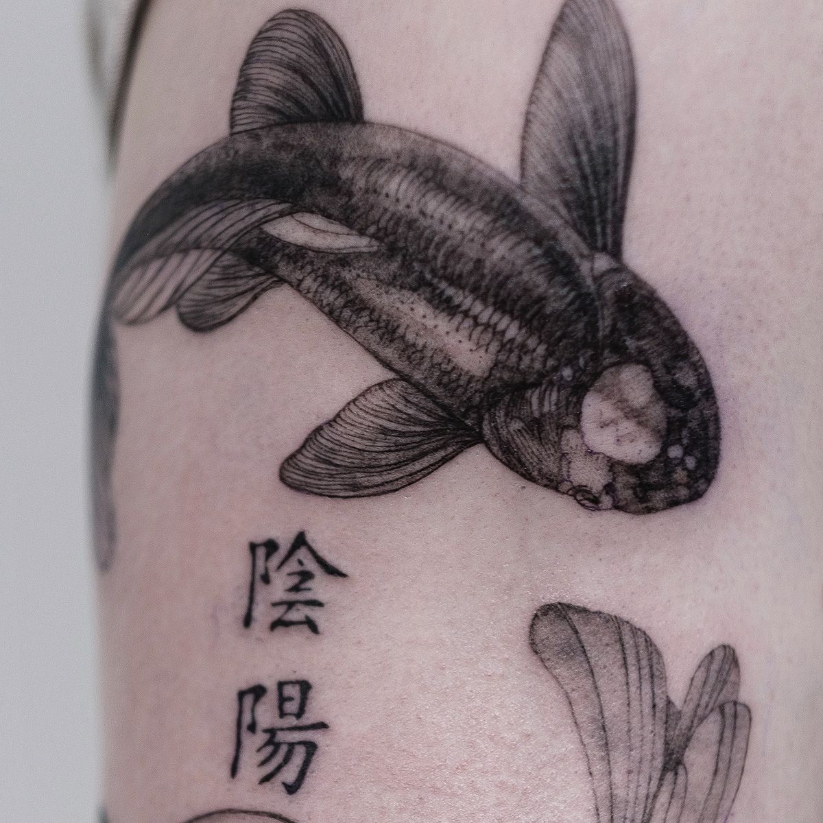 Gedetailleerde zwart-grijze koi vis met Chinese tekens op bovenarm.