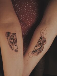 Twee onderarmen met realistische leeuw en leeuwin tattoos en geometrische lijnen.
