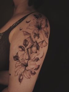 Draakje tussen bloemen en maantjes op bovenarm.