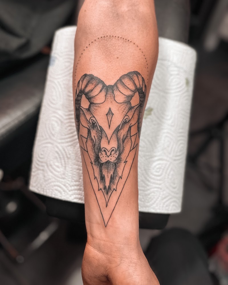 Blackwork ram hoofd in geometrische driehoek op onderarm.