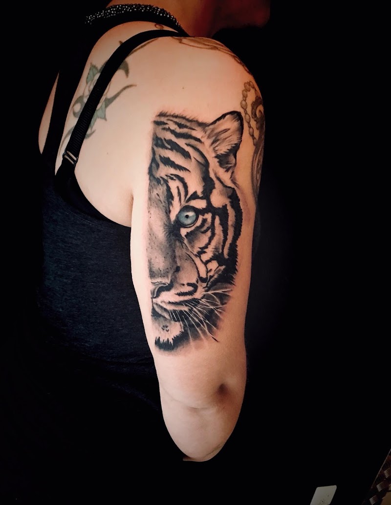 Realistische halve tijgerkop met blauw oog op bovenarm.
